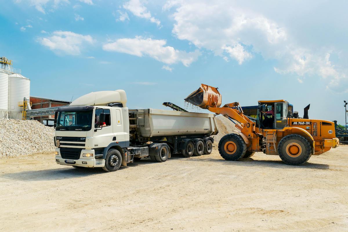 brown loader beside white cargo truck