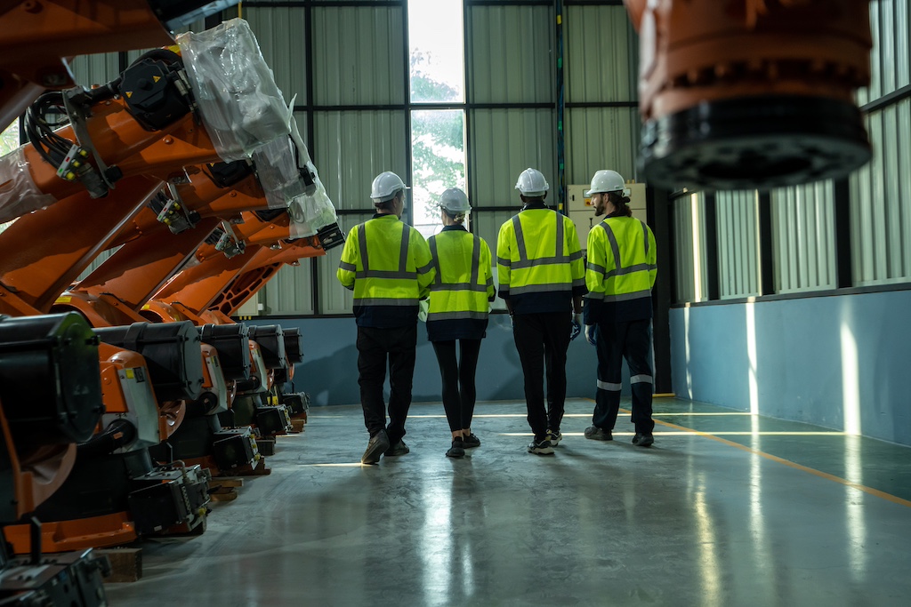 Robotics engineers inspect and maintain spare parts of industrial robot arm controller in production plant factory.