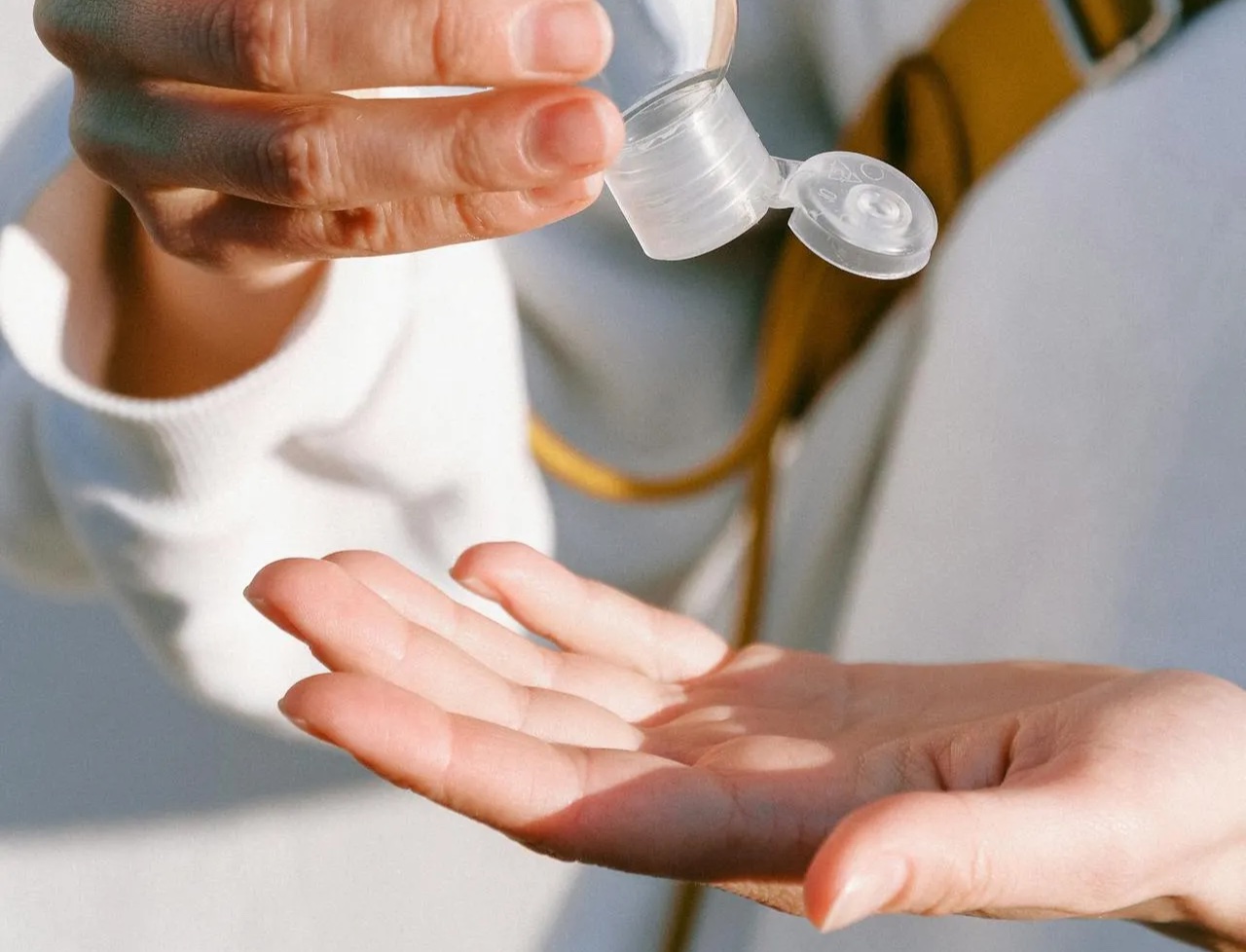 Person in white long sleeve shirt holding clear bottle