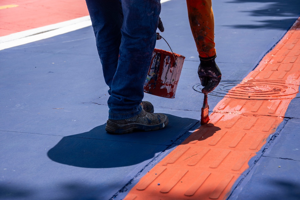 A person painting a red line on the street