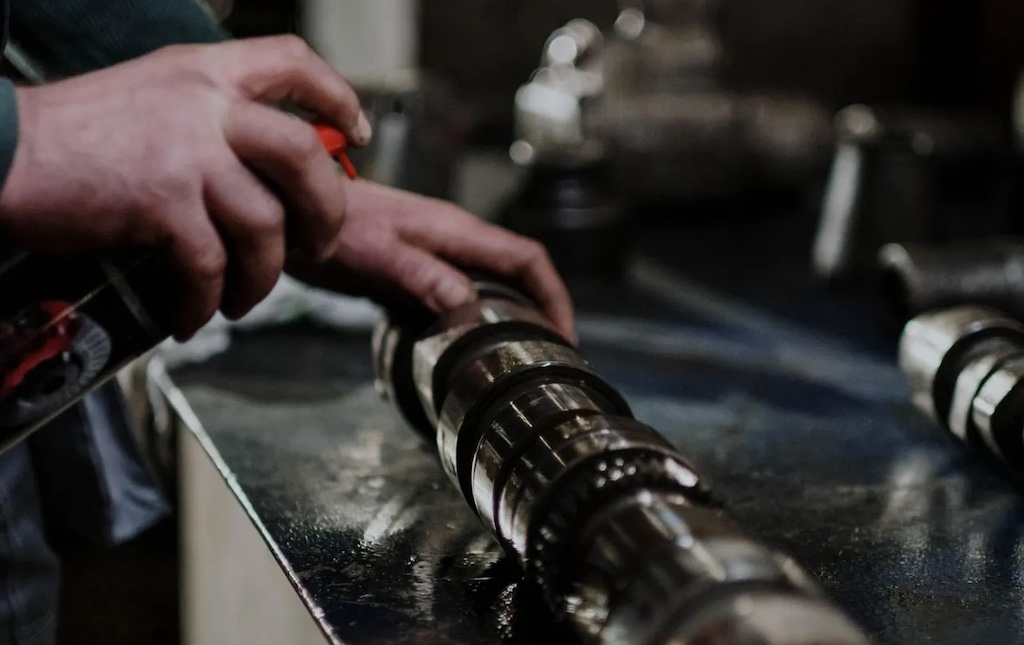 A person greasing a part of a metal engine