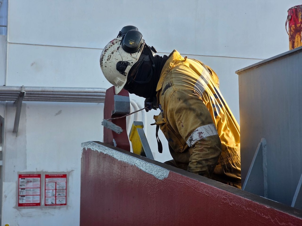 Industrial worker painting metal structure