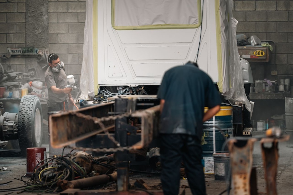 Industrial workshop with workers painting vehicle