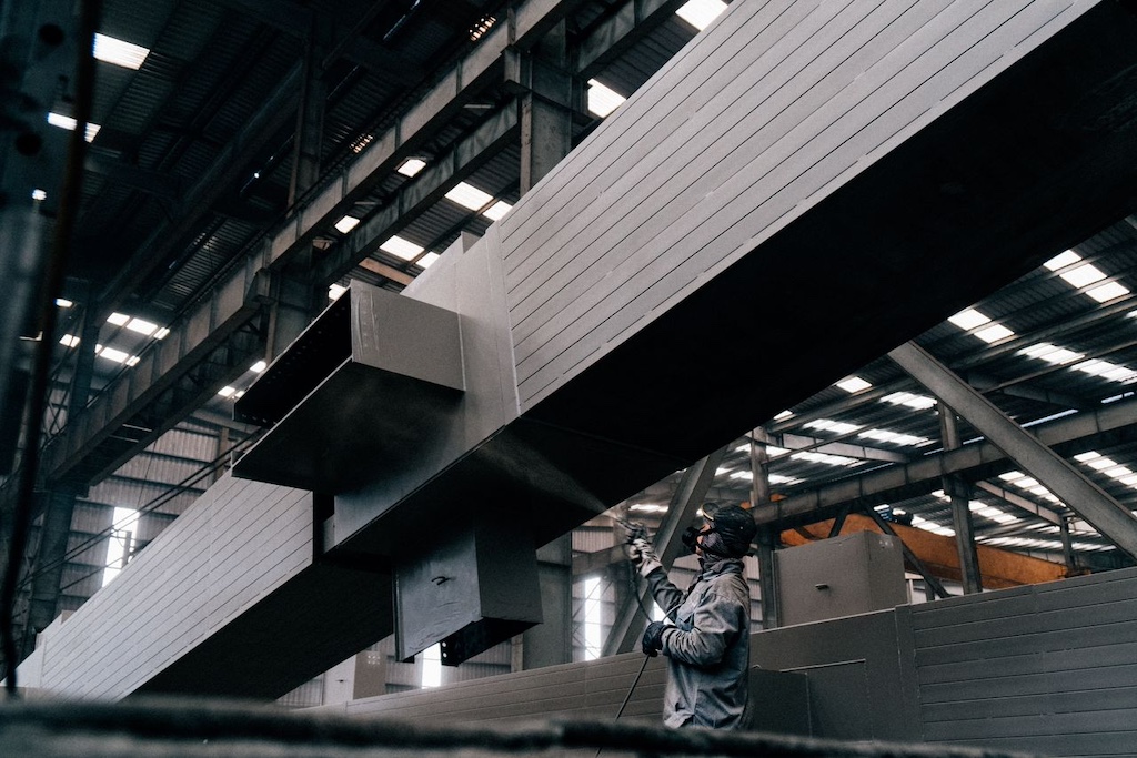 Man in worker suit spraying on metal structure