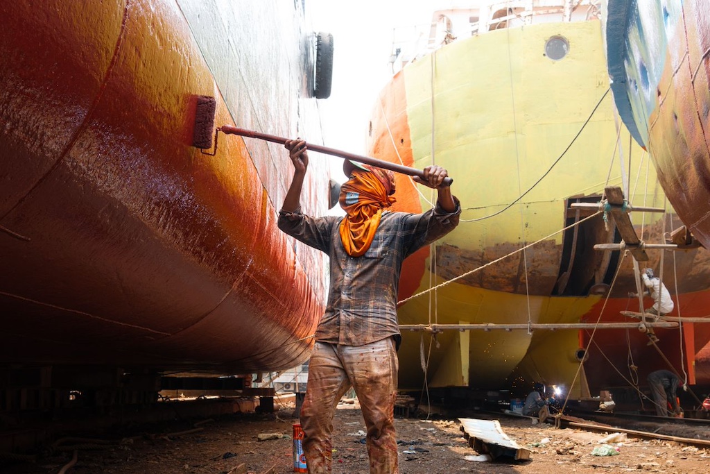 Shipyard worker painting a vessel in dry dock